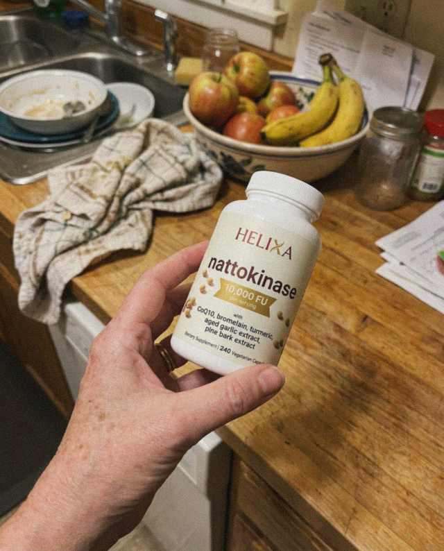 Customer holding the Helixa Nattokinase bottle in her kitchen