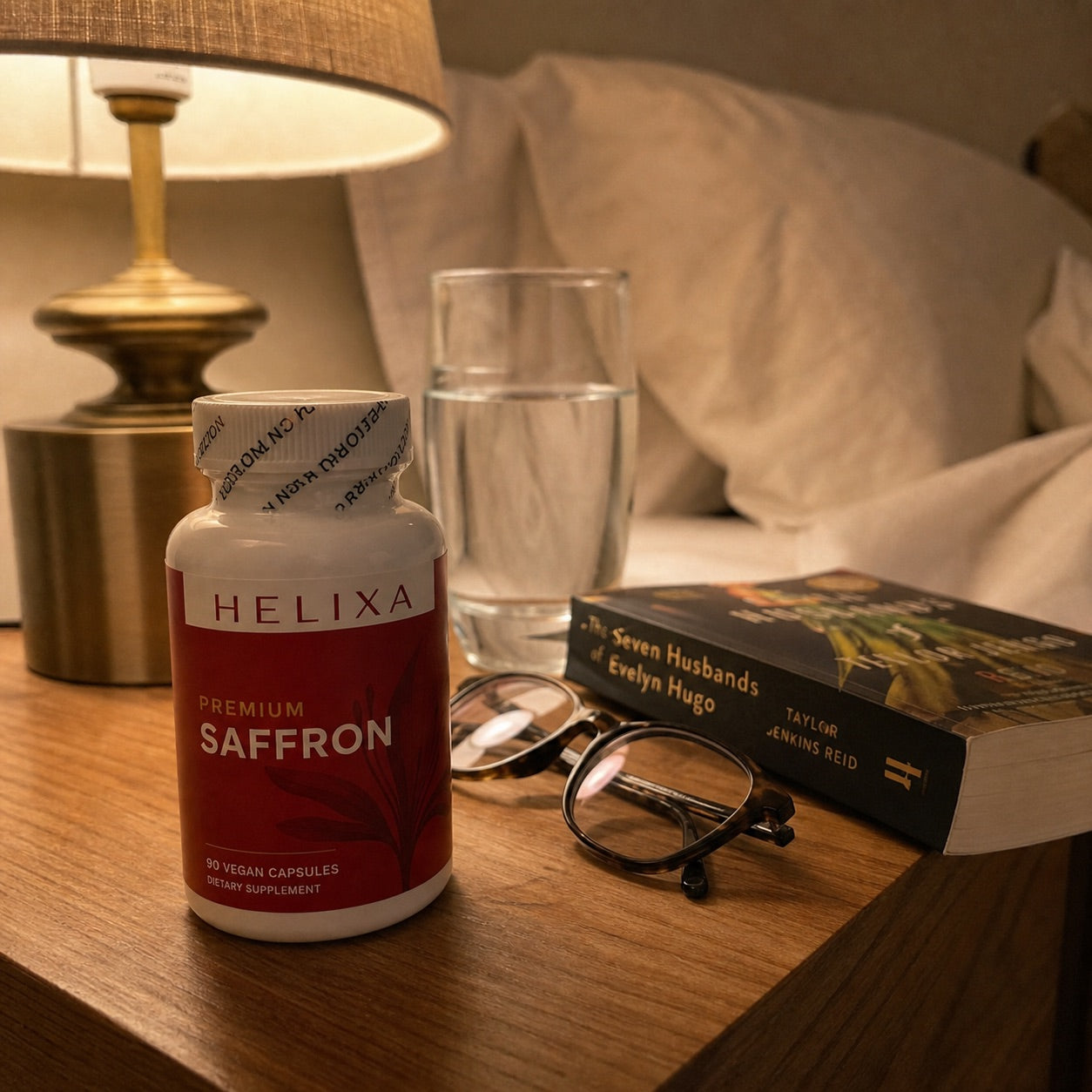 Helixa Premium Saffron bottle on a bedside table with water and a book