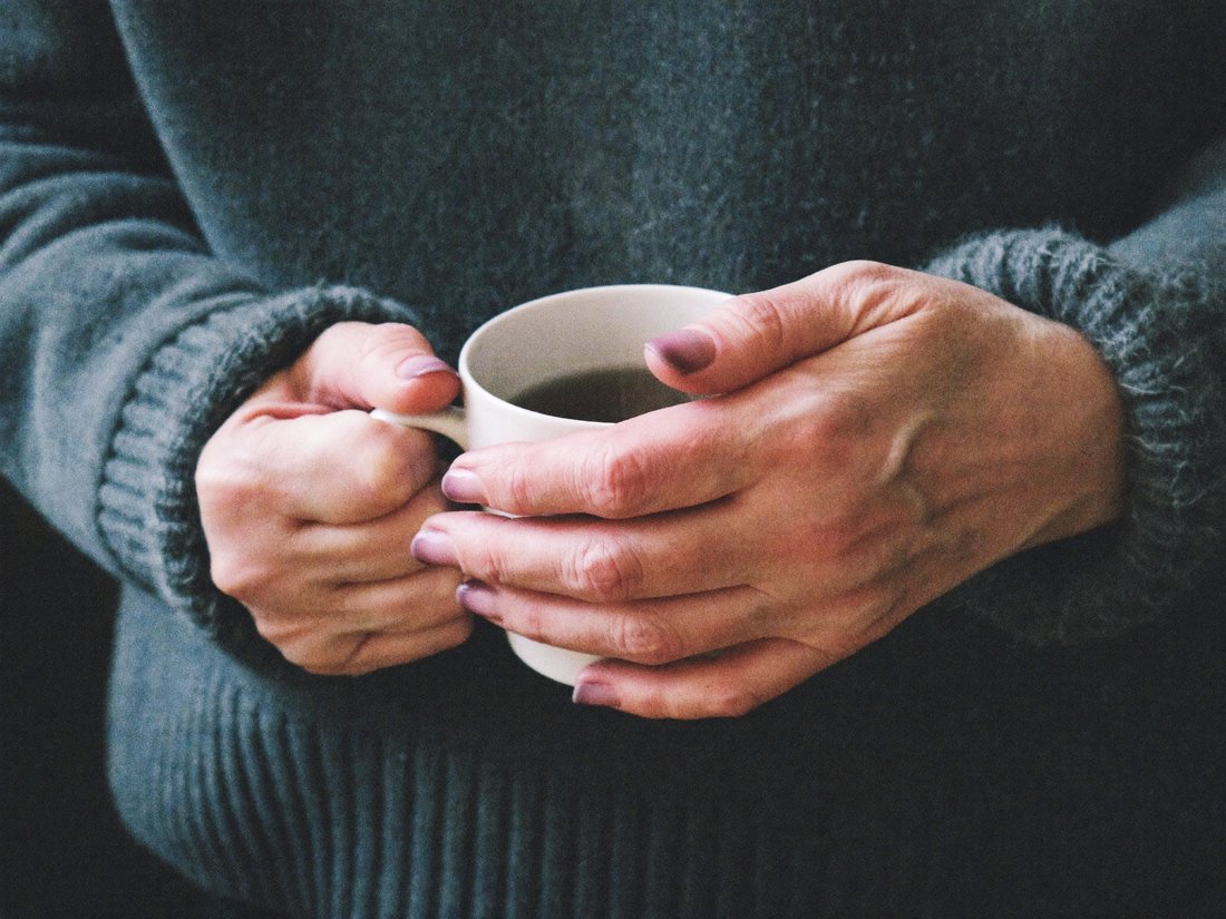 Cold hands wrapped around a warm mug